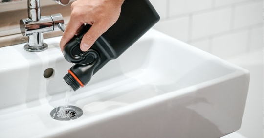 A homeowner using a chemical drain cleaner.
